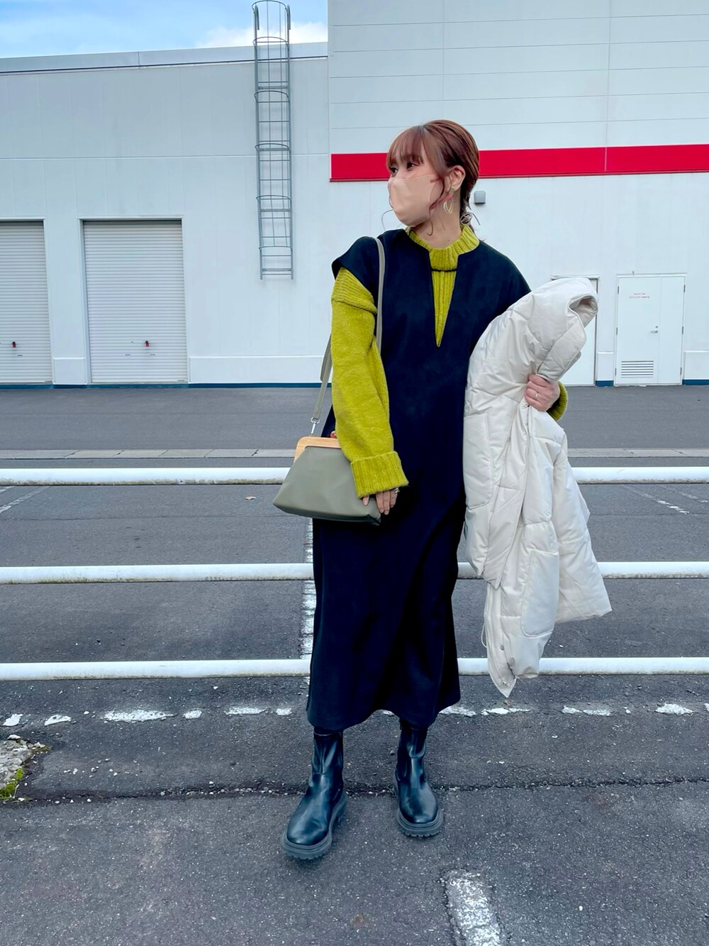 ホワイト系のジャケット/アウター、グリーン系のニット/セーター、ブラック系のワンピース/ドレスを着用したレディースの冬コーディネートの3枚目の写真