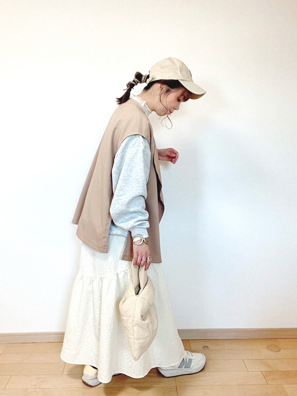 グレー系のスウェット、ベージュ系のベスト、ホワイト系のスカートを着用したレディースの春コーディネートの2枚目の写真