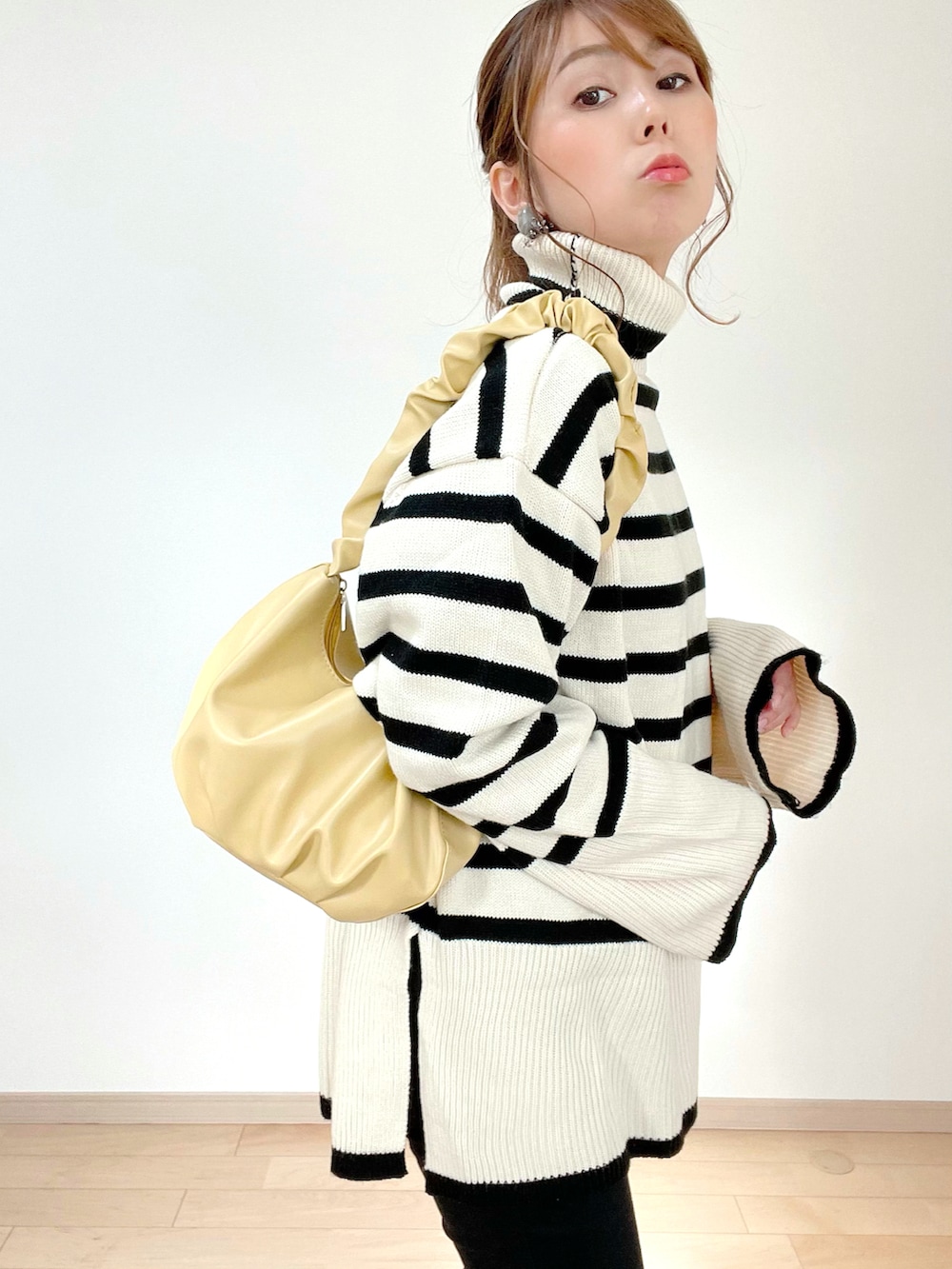 ベージュ系のニット/セーター、ブラック系のその他パンツ、イエロー系のハンドバッグを着用したレディースの冬コーディネートの4枚目の写真