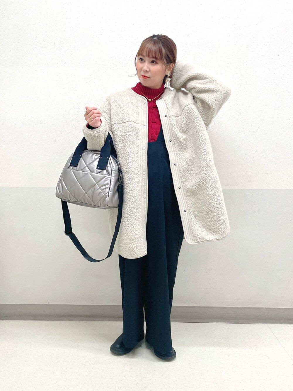レッド系のニット/セーター、ベージュ系のサロペット/オーバーオール、シルバー系のトートバッグを着用したレディースの冬コーディネートの2枚目の写真