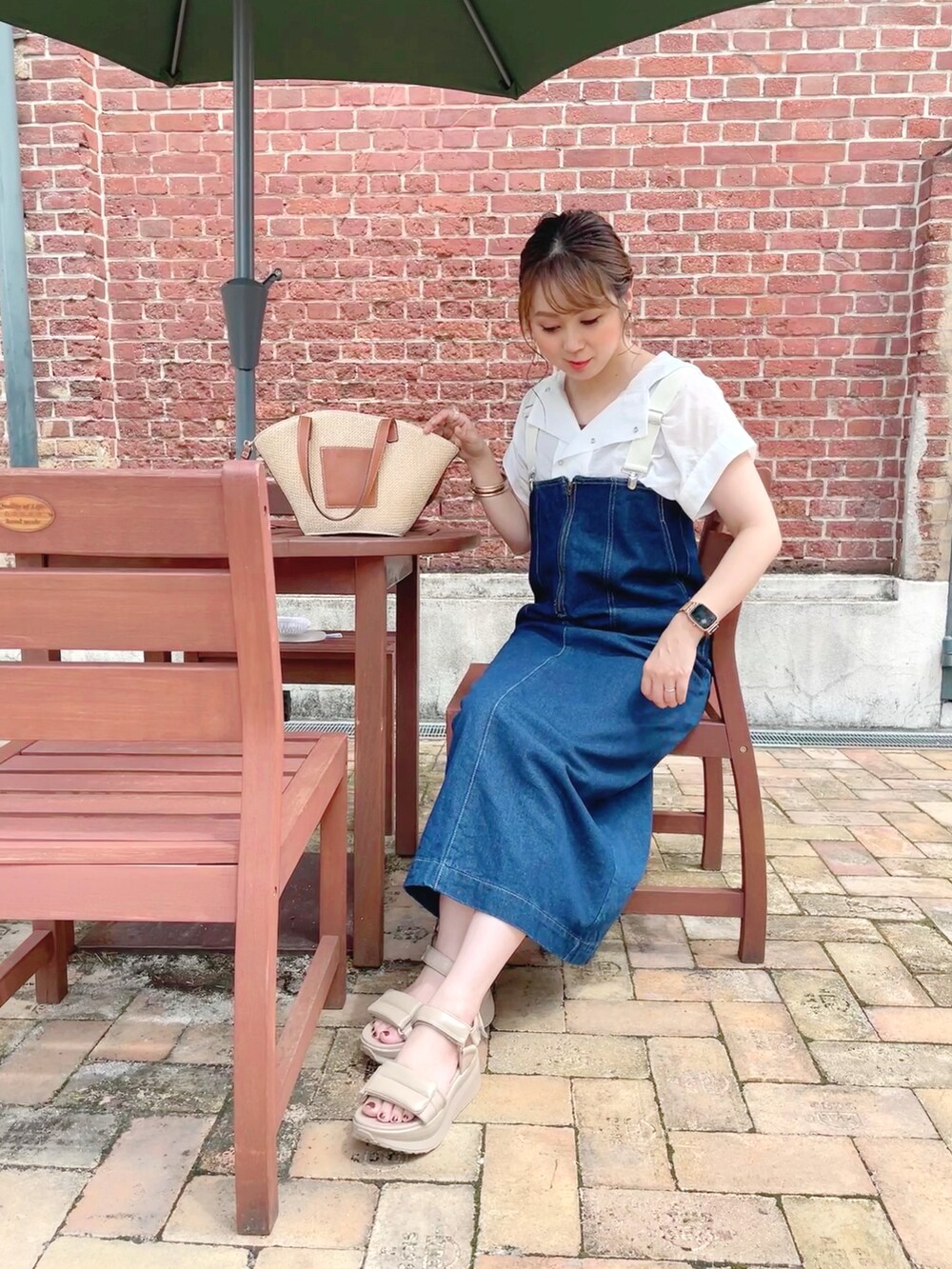 ホワイト系のトップス、ブルー系のオールインワン・サロペット、ブラウン系のタンクトップを着用したレディースの夏コーディネートの2枚目の写真