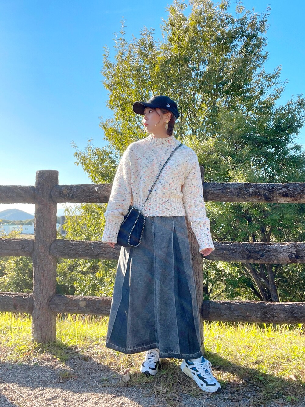 ホワイト系のニット/セーター、ブラック系のデニムスカート、ブラック系のハンドバッグを着用したレディースの秋コーディネートの2枚目の写真