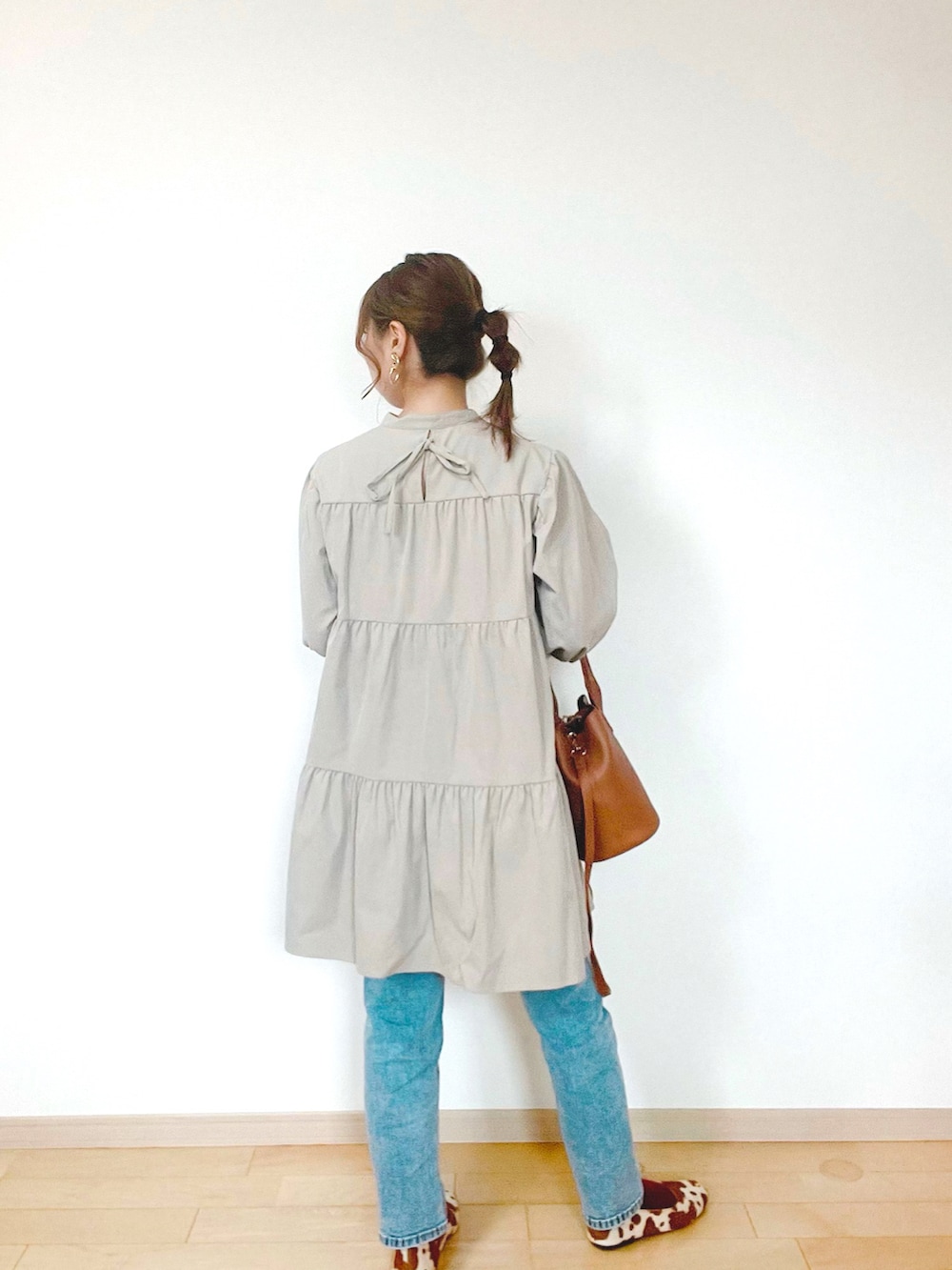 ブルー系のデニムパンツ、ベージュ系のワンピース、ブラウン系のバッグを着用したレディースの秋コーディネートの5枚目の写真