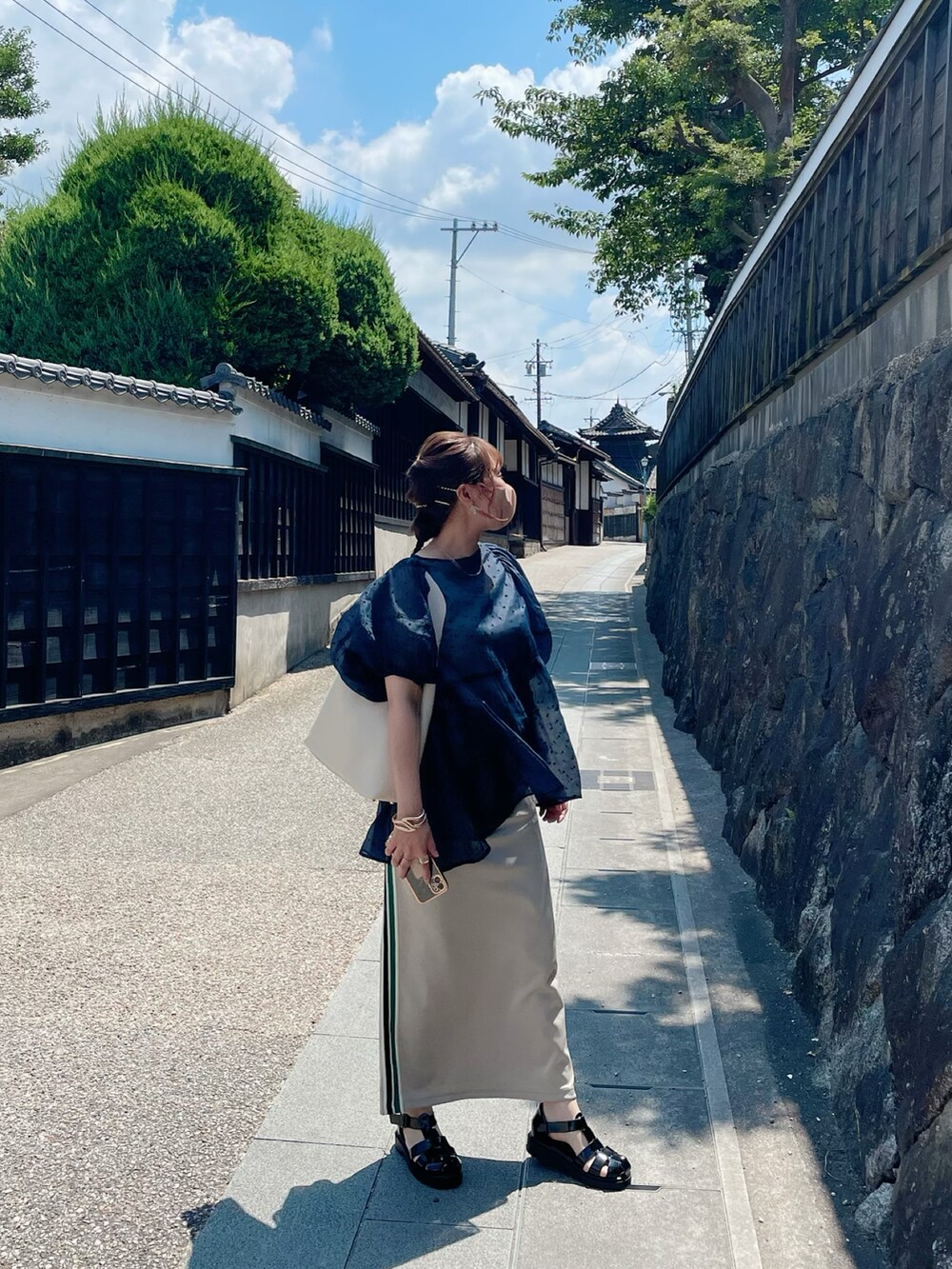 ブラック系のサンダル、ベージュ系のスカート、ホワイト系のバッグを着用したレディースの夏コーディネートの2枚目の写真