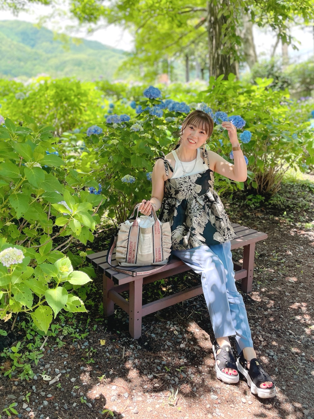 ブラック系のキャミソール、ホワイト系のタンクトップ、ベージュ系のショルダーバッグを着用したレディースの夏コーディネートの3枚目の写真