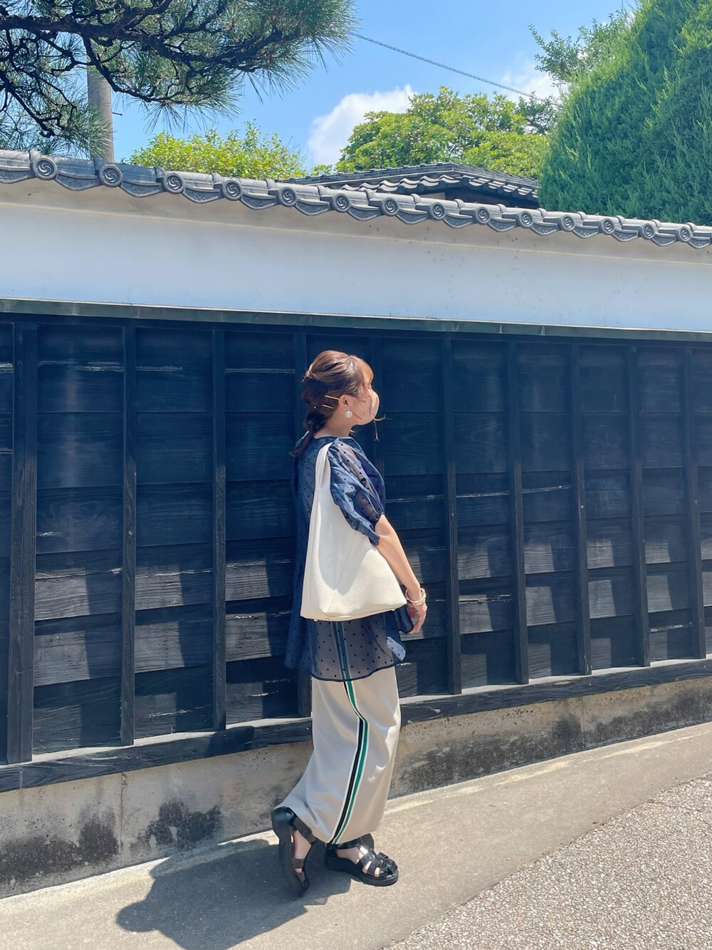 ブラック系のサンダル、ベージュ系のスカート、ホワイト系のバッグを着用したレディースの夏コーディネートの4枚目の写真