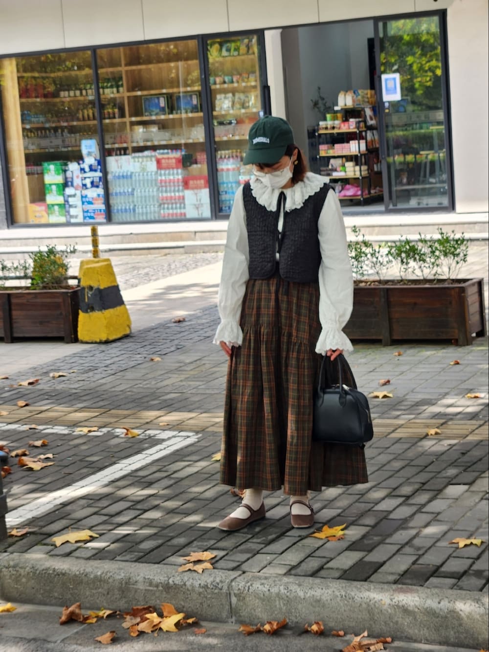 ブラック系のベスト、ホワイト系のシャツ/ブラウス、ブラウン系のスカートを着用したレディースの秋コーディネートの2枚目の写真