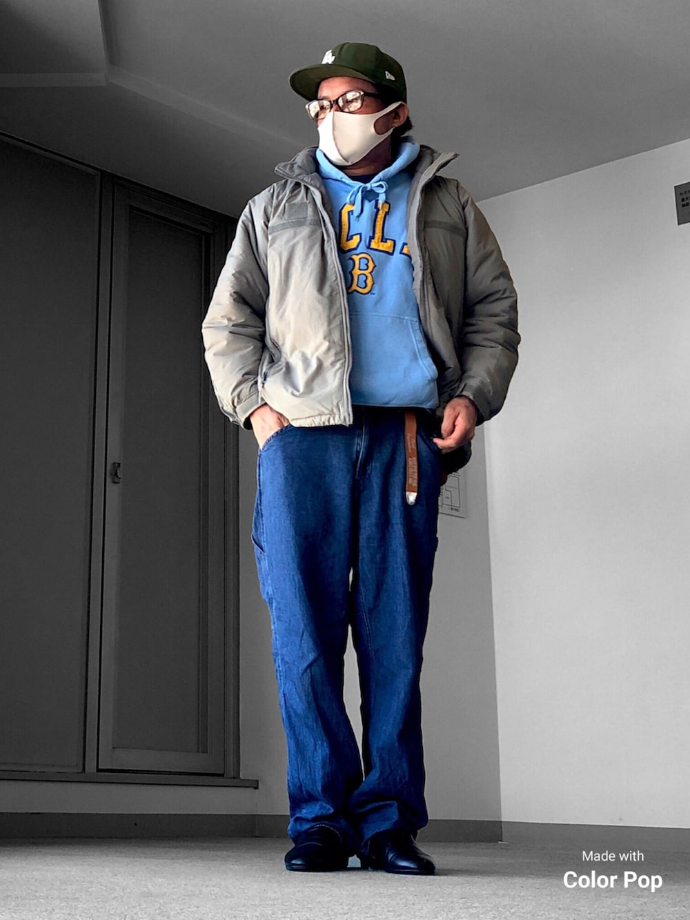 グリーン系のブルゾン、ブルー系のパーカー、ブルー系のデニムパンツを着用したメンズの冬コーディネートの3枚目の写真