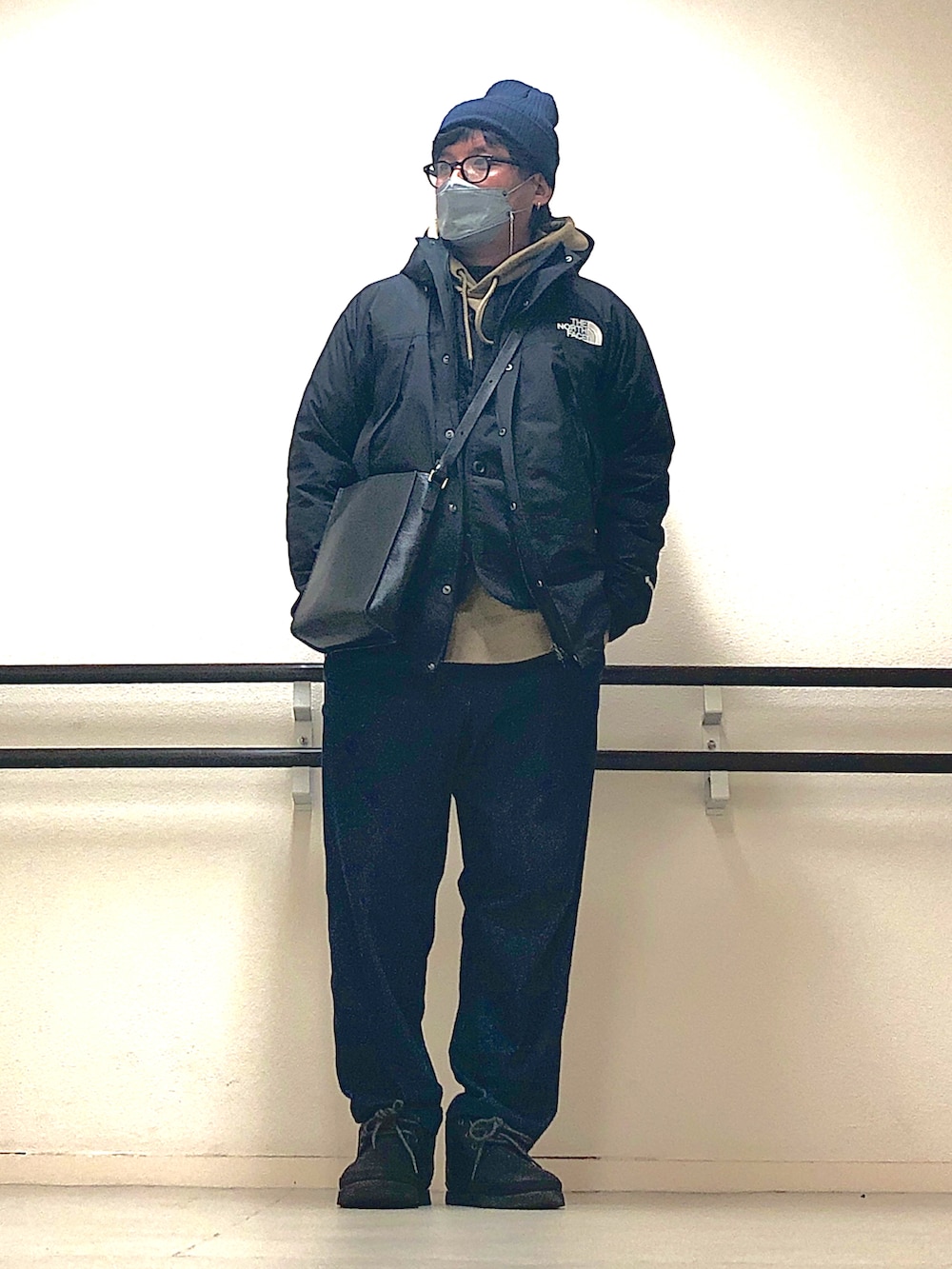 ベージュ系のパーカー、ブラック系のマウンテンパーカー、ブラック系のショルダーバッグを着用したメンズの冬コーディネートの2枚目の写真