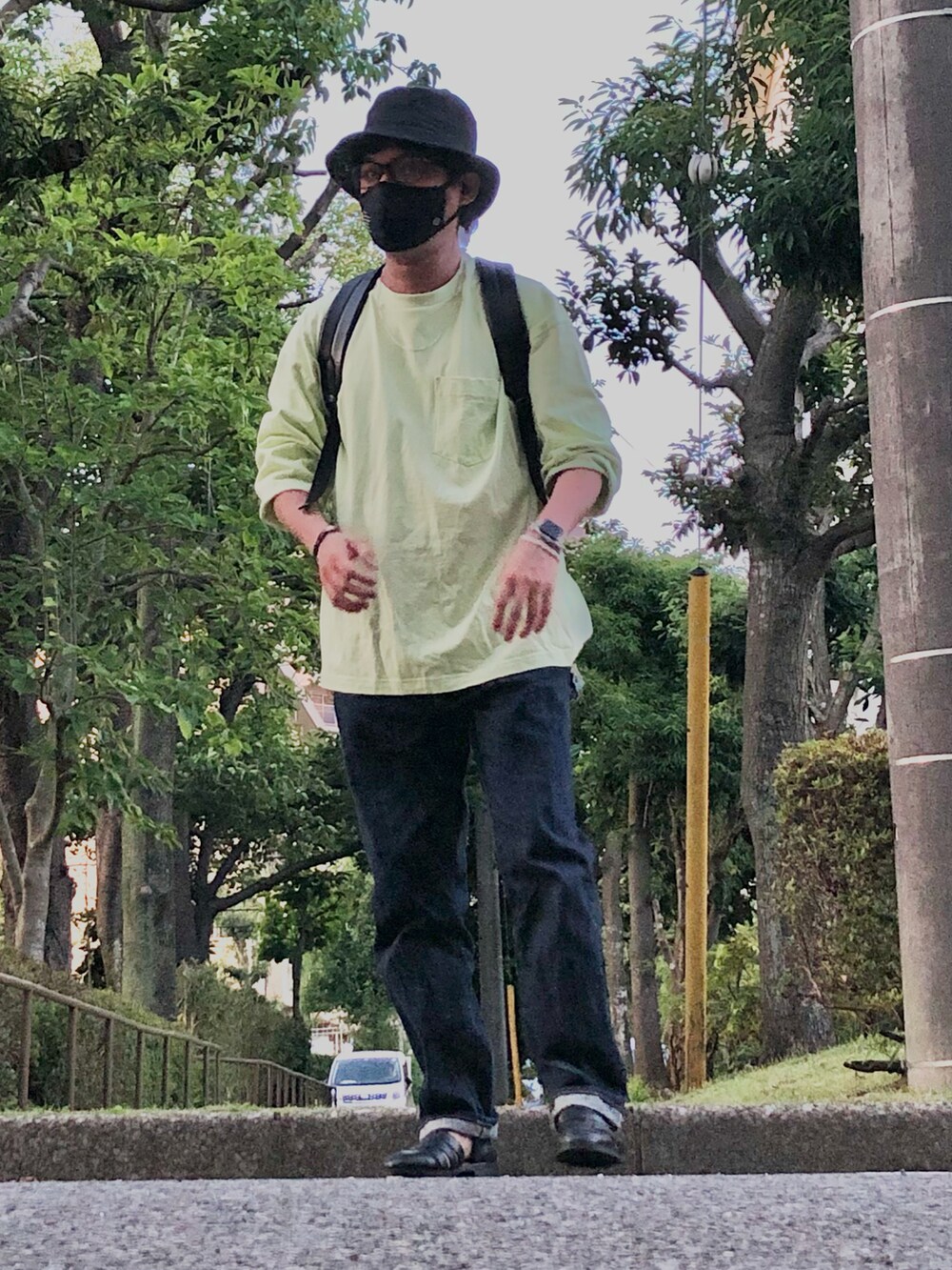 ブラック系のバックパック/リュック、グリーン系のTシャツ/カットソー、ブルー系のデニムパンツを着用したメンズの夏コーディネートの4枚目の写真