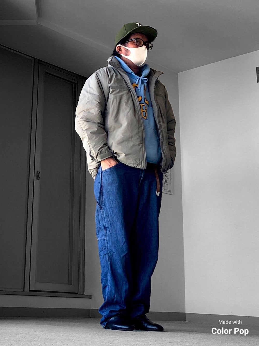 グリーン系のブルゾン、ブルー系のパーカー、ブルー系のデニムパンツを着用したメンズの冬コーディネートの2枚目の写真