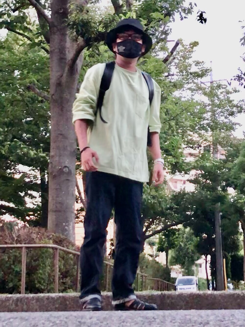 ブラック系のバックパック/リュック、グリーン系のTシャツ/カットソー、ブルー系のデニムパンツを着用したメンズの夏コーディネートの3枚目の写真