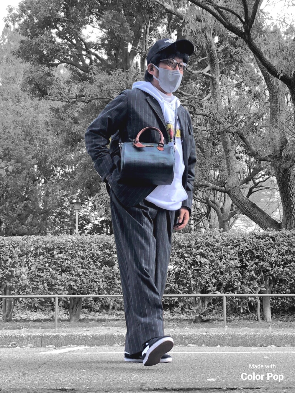 ホワイト系のパーカー、ブラック系のカバーオール、グリーン系のボストンバッグを着用したメンズの秋コーディネートの2枚目の写真