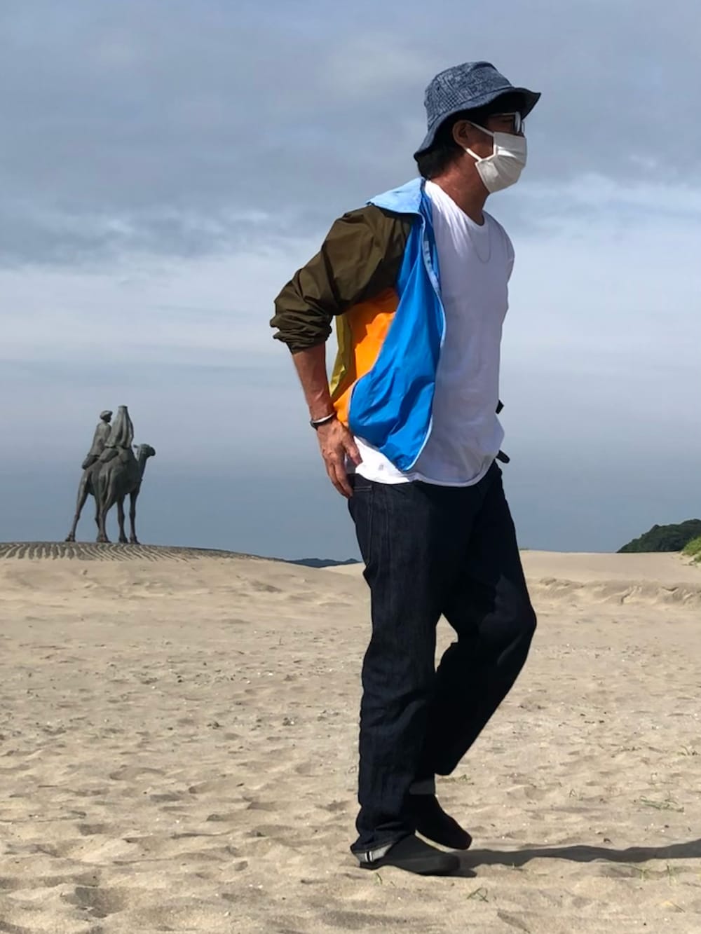 その他のナイロンジャケット、ブルー系のデニムパンツ、ブラック系のスニーカーを着用したメンズの夏コーディネートの3枚目の写真