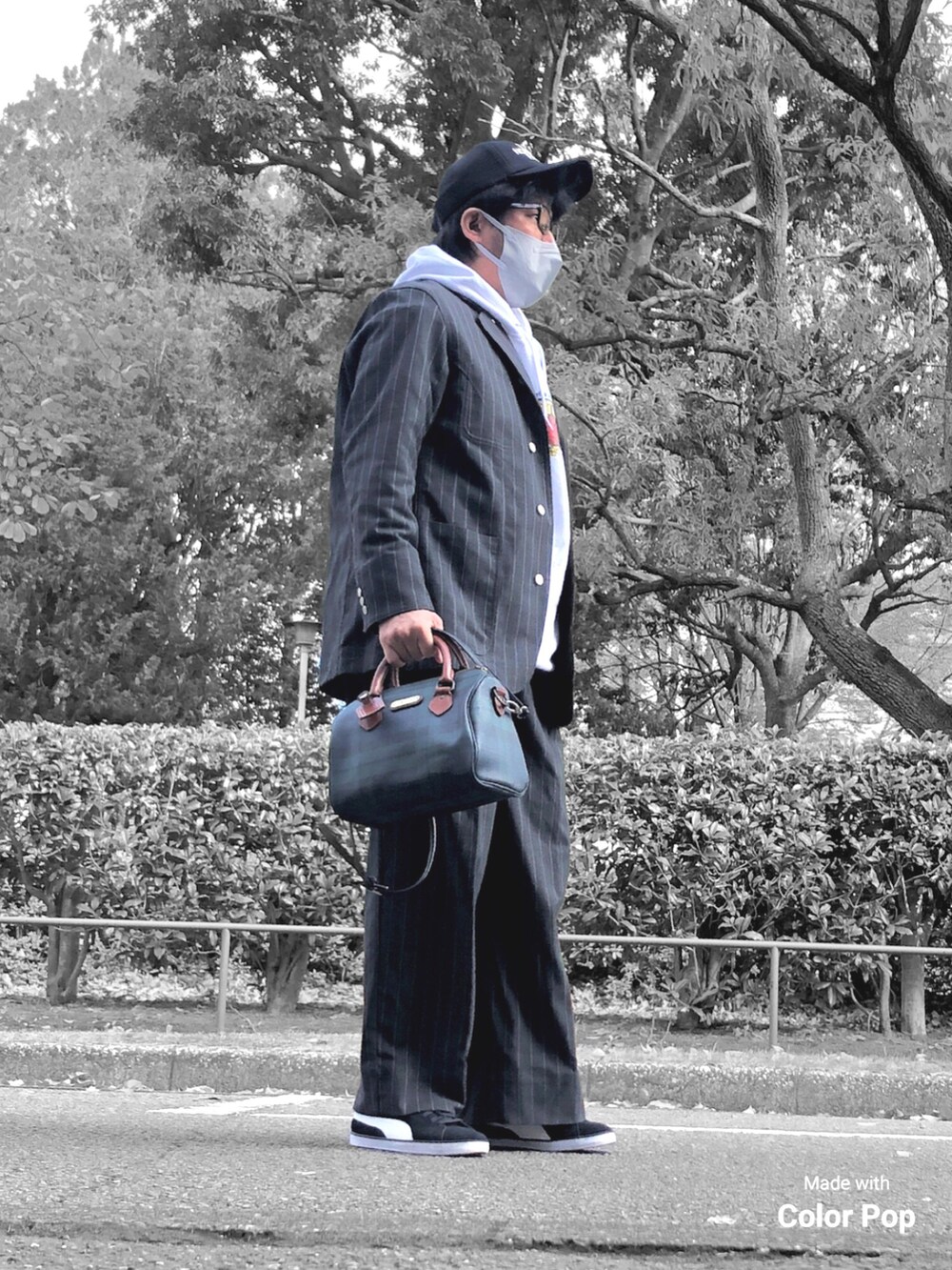 ホワイト系のパーカー、ブラック系のカバーオール、グリーン系のボストンバッグを着用したメンズの秋コーディネートの5枚目の写真