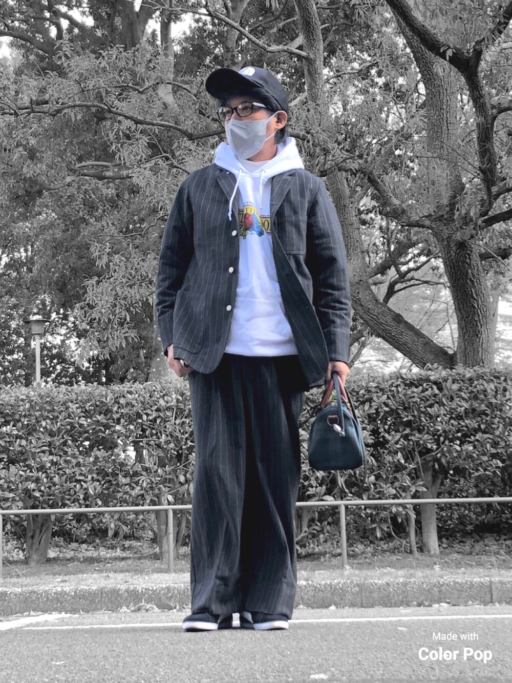 ホワイト系のパーカー、ブラック系のカバーオール、グリーン系のボストンバッグを着用したメンズの秋コーディネートの4枚目の写真