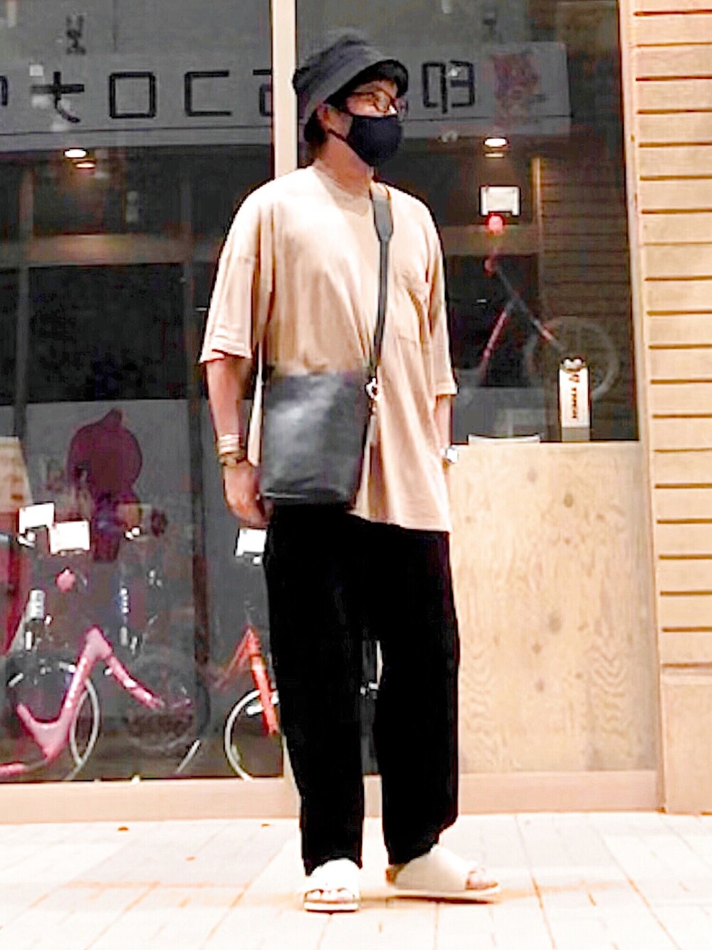 ブラック系のショルダーバッグ、ベージュ系のTシャツ/カットソー、ベージュ系のサンダルを着用したメンズの夏コーディネートの3枚目の写真