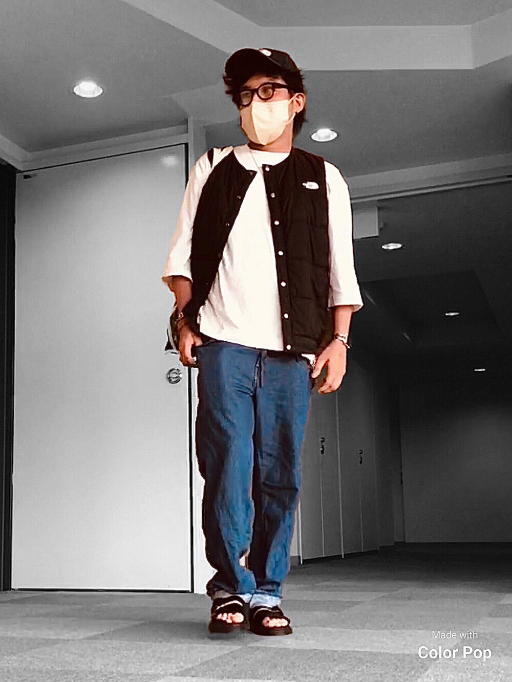 ブラック系のダウンベスト、ホワイト系のTシャツ/カットソー、ブルー系のデニムパンツを着用したメンズの秋コーディネートの2枚目の写真