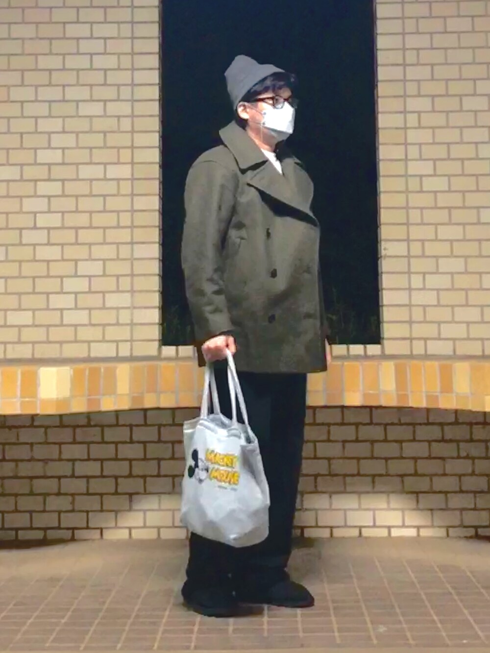 グリーン系のピーコート、ホワイト系のTシャツ/カットソー、グレー系のエコバッグ/サブバッグを着用したメンズの冬コーディネートの2枚目の写真