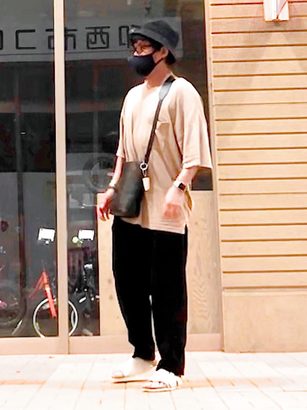 ブラック系のショルダーバッグ、ベージュ系のTシャツ/カットソー、ベージュ系のサンダルを着用したメンズの夏コーディネートの2枚目の写真