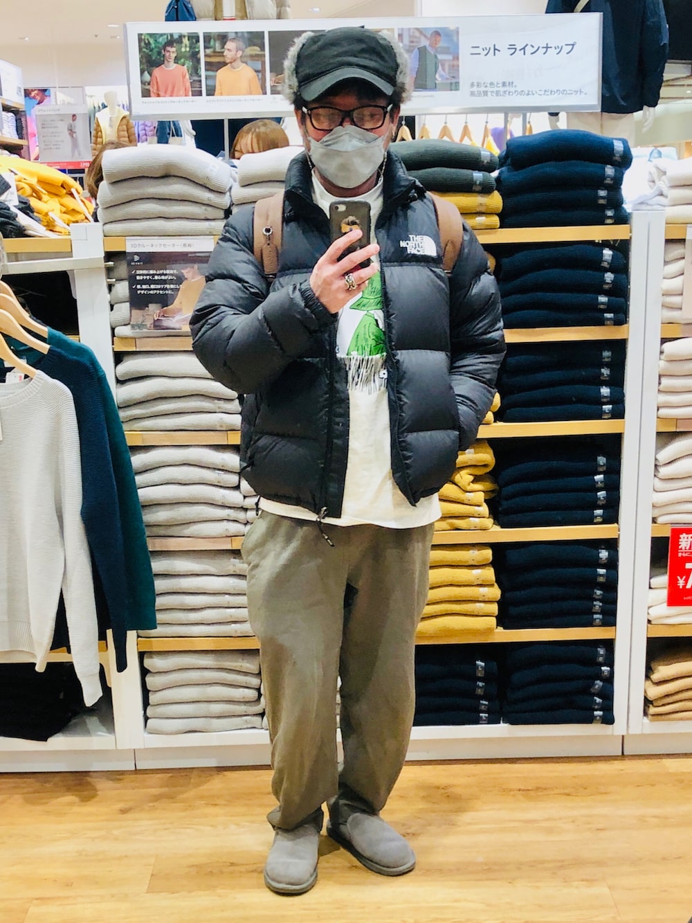 ブラック系のダウンジャケット/コート、ブラウン系のバックパック/リュック、ベージュ系のTシャツ/カットソーを着用したメンズの冬コーディネートの2枚目の写真