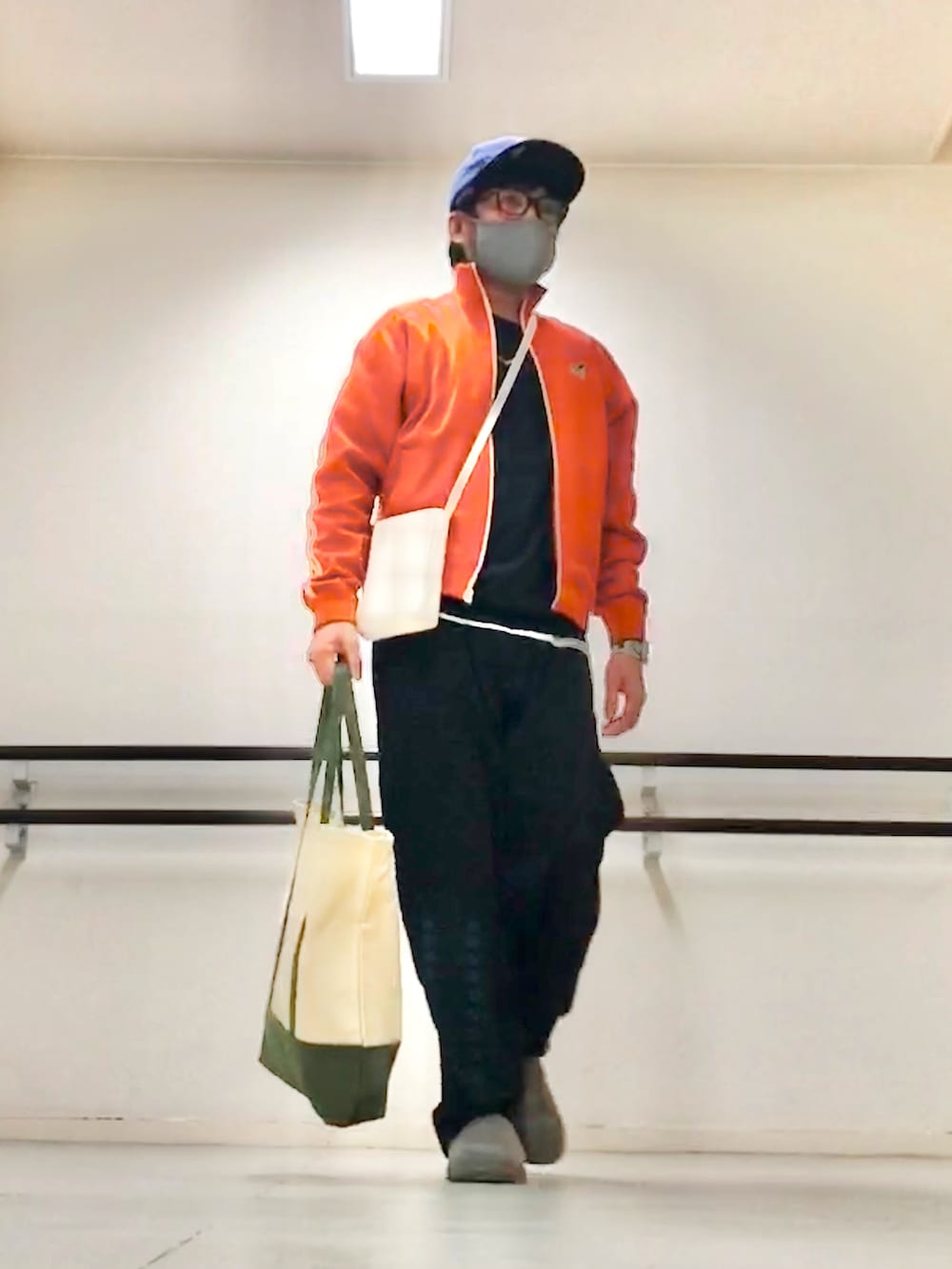 オレンジ系のジャージ、ブラック系のニット/セーター、ブラック系のスウェットパンツを着用したメンズの秋コーディネートの2枚目の写真