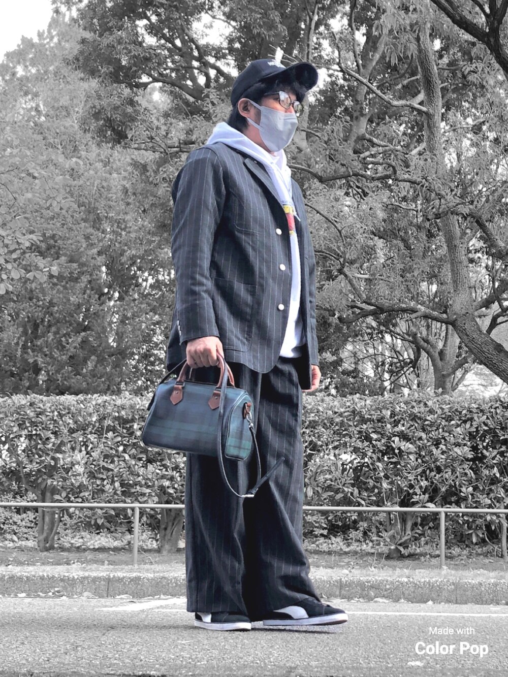 ホワイト系のパーカー、ブラック系のカバーオール、グリーン系のボストンバッグを着用したメンズの秋コーディネートの3枚目の写真