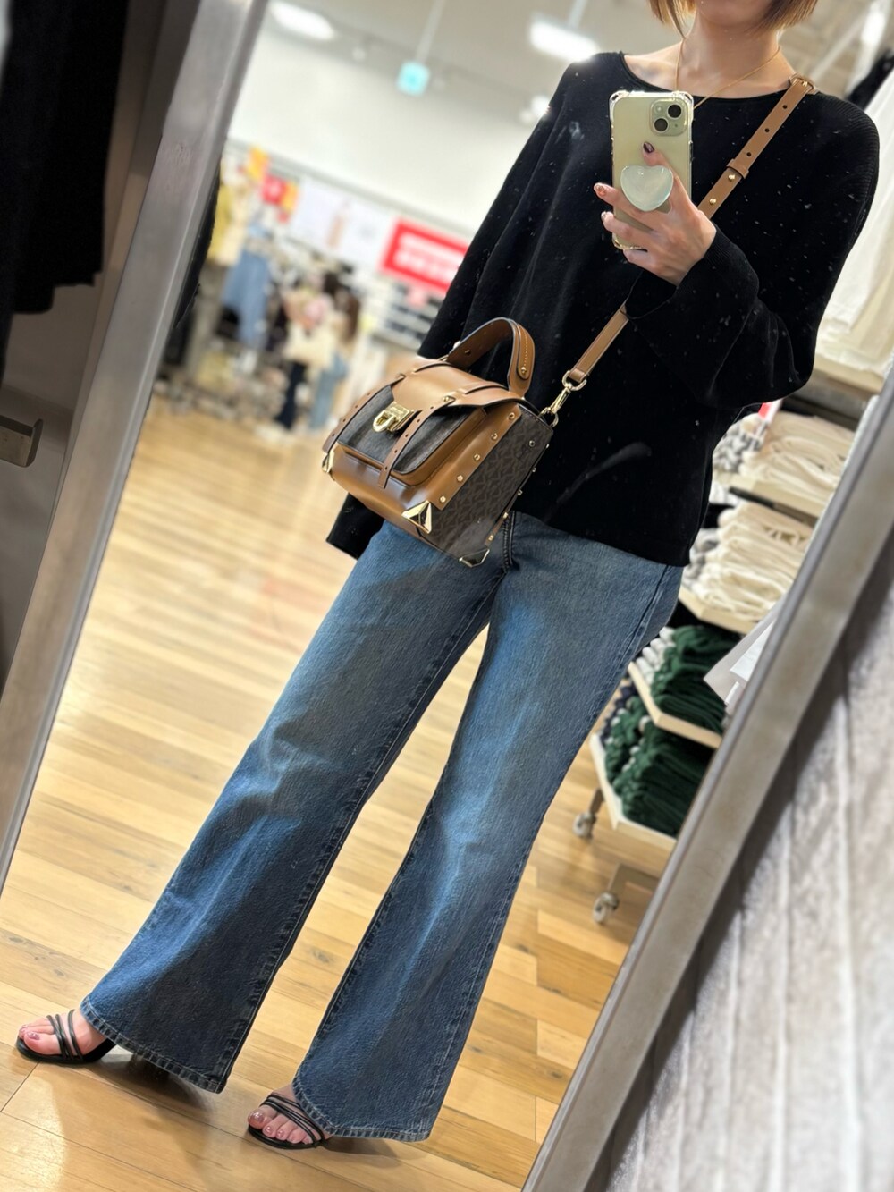 ブルー系のデニムパンツ、ブラック系のニット/セーター、ブラウン系のハンドバッグを着用したレディースの春コーディネートの2枚目の写真