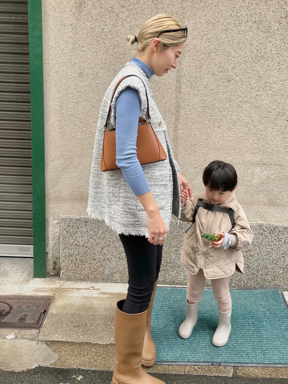 ブルー系のニット/セーター、ブラウン系のハンドバッグ、ホワイト系のベストを着用したレディースの春コーディネートの2枚目の写真