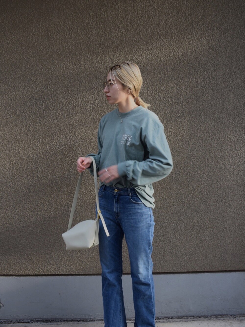 グリーン系のTシャツ/カットソー、ブルー系のデニムパンツ、ベージュ系のブーツを着用したレディースの春コーディネートの2枚目の写真