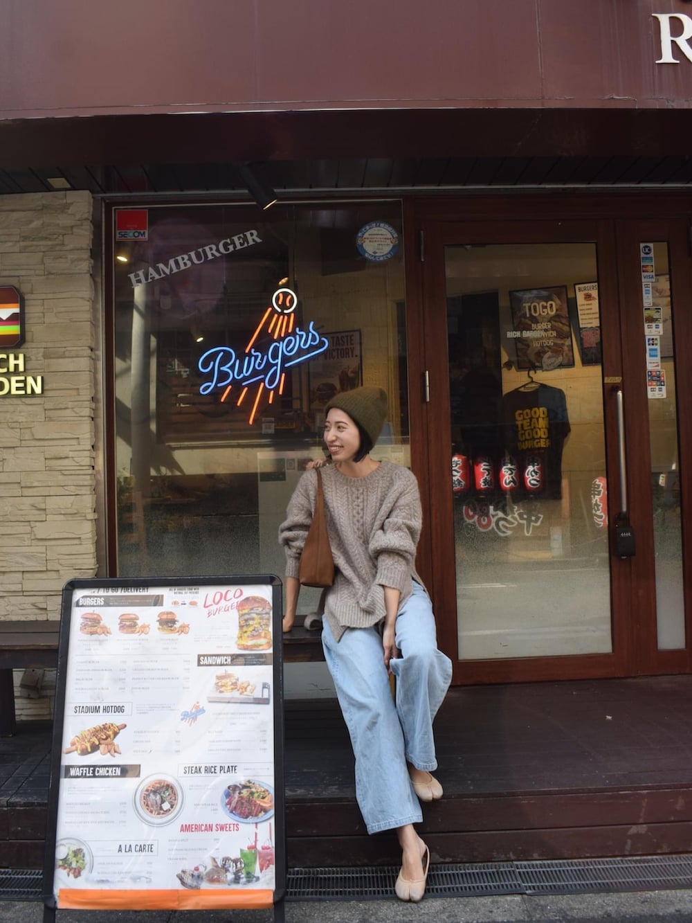 ベージュ系のニット/セーター、ブルー系のデニムパンツ、イエロー系のハンドバッグを着用したレディースの秋コーディネートの3枚目の写真