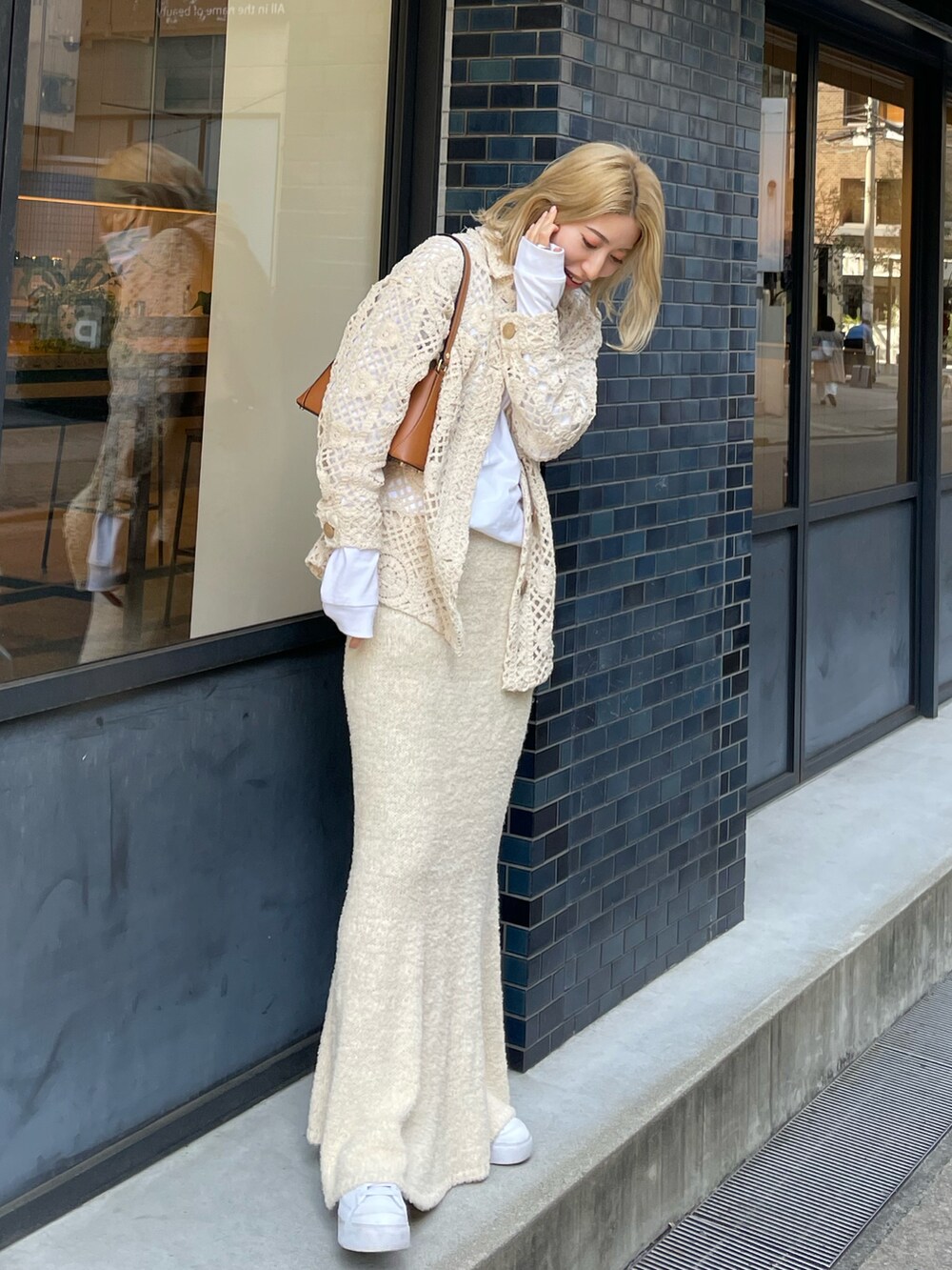 ホワイト系のスカート、ブラウン系のハンドバッグ、ホワイト系のスニーカーを着用したレディースの春コーディネートの2枚目の写真