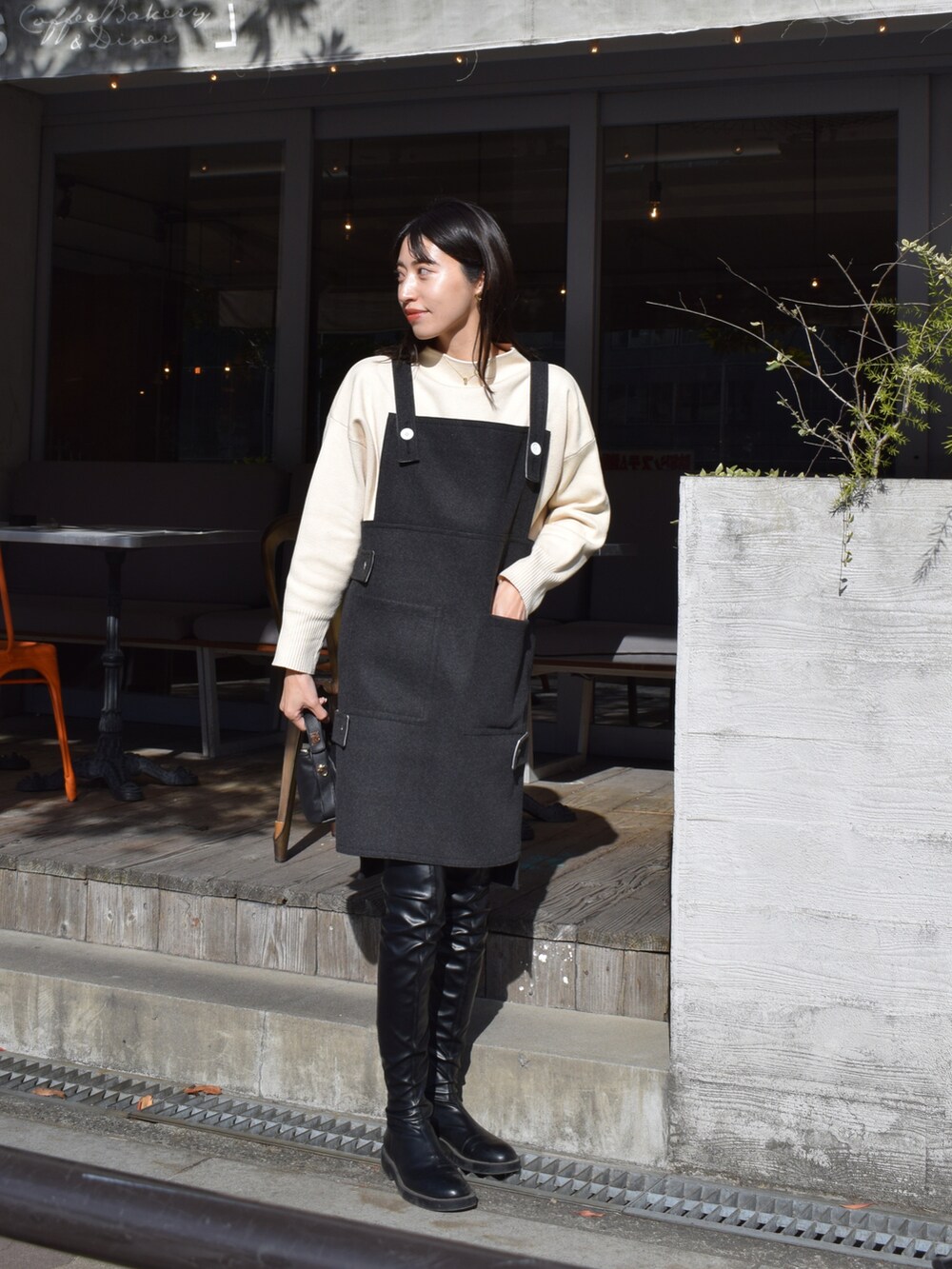 グレー系のワンピース/ドレス、ホワイト系のニット/セーター、ブラック系のブーツを着用したレディースの冬コーディネートの2枚目の写真