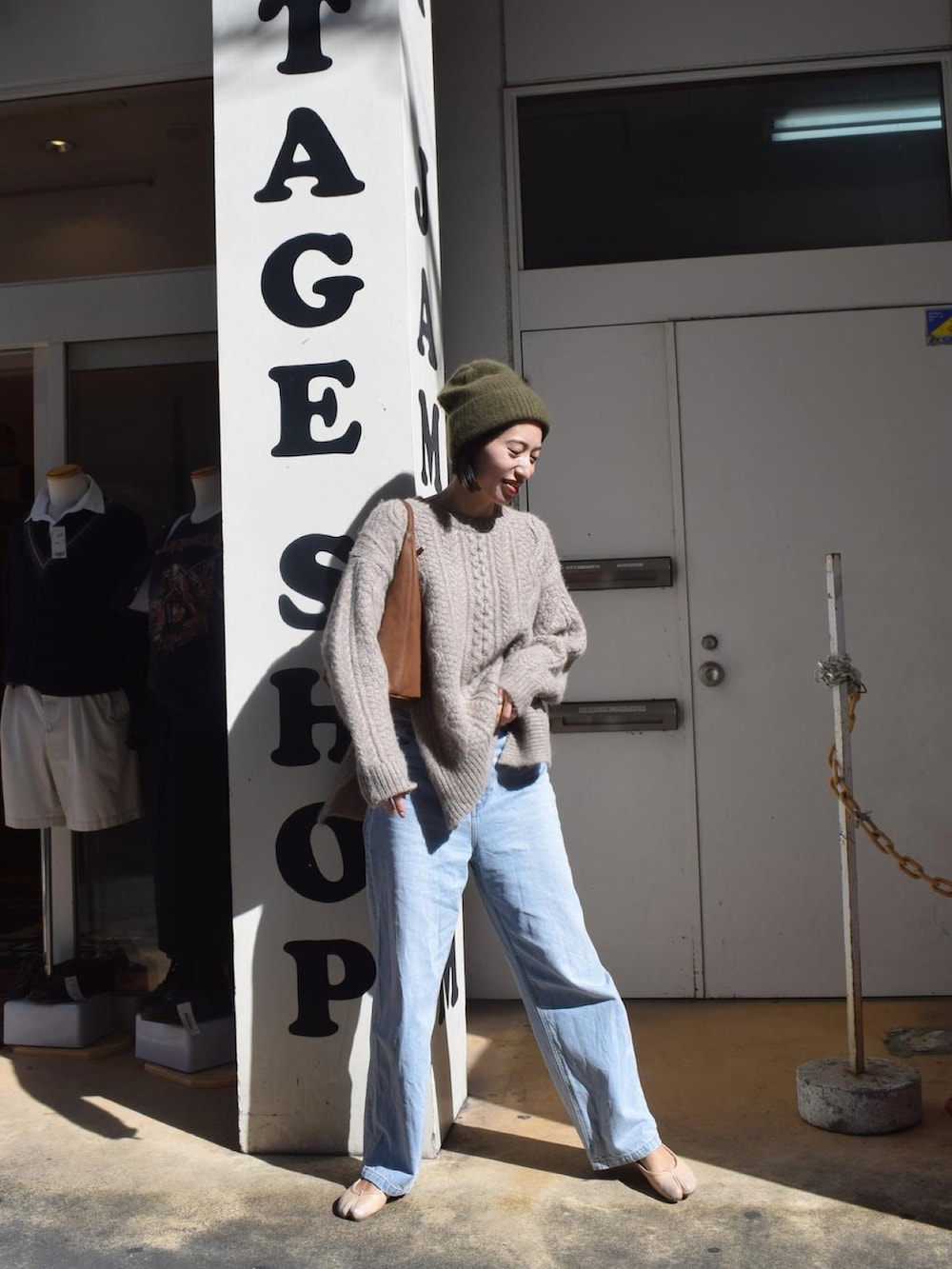 ベージュ系のニット/セーター、ブルー系のデニムパンツ、イエロー系のハンドバッグを着用したレディースの秋コーディネートの2枚目の写真