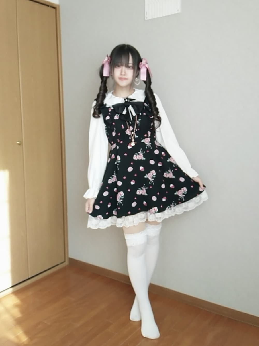 ブラック系のワンピース、ピンク系のカーディガン/ボレロ、ピンク系のバッグを着用したレディースの冬コーディネートの2枚目の写真