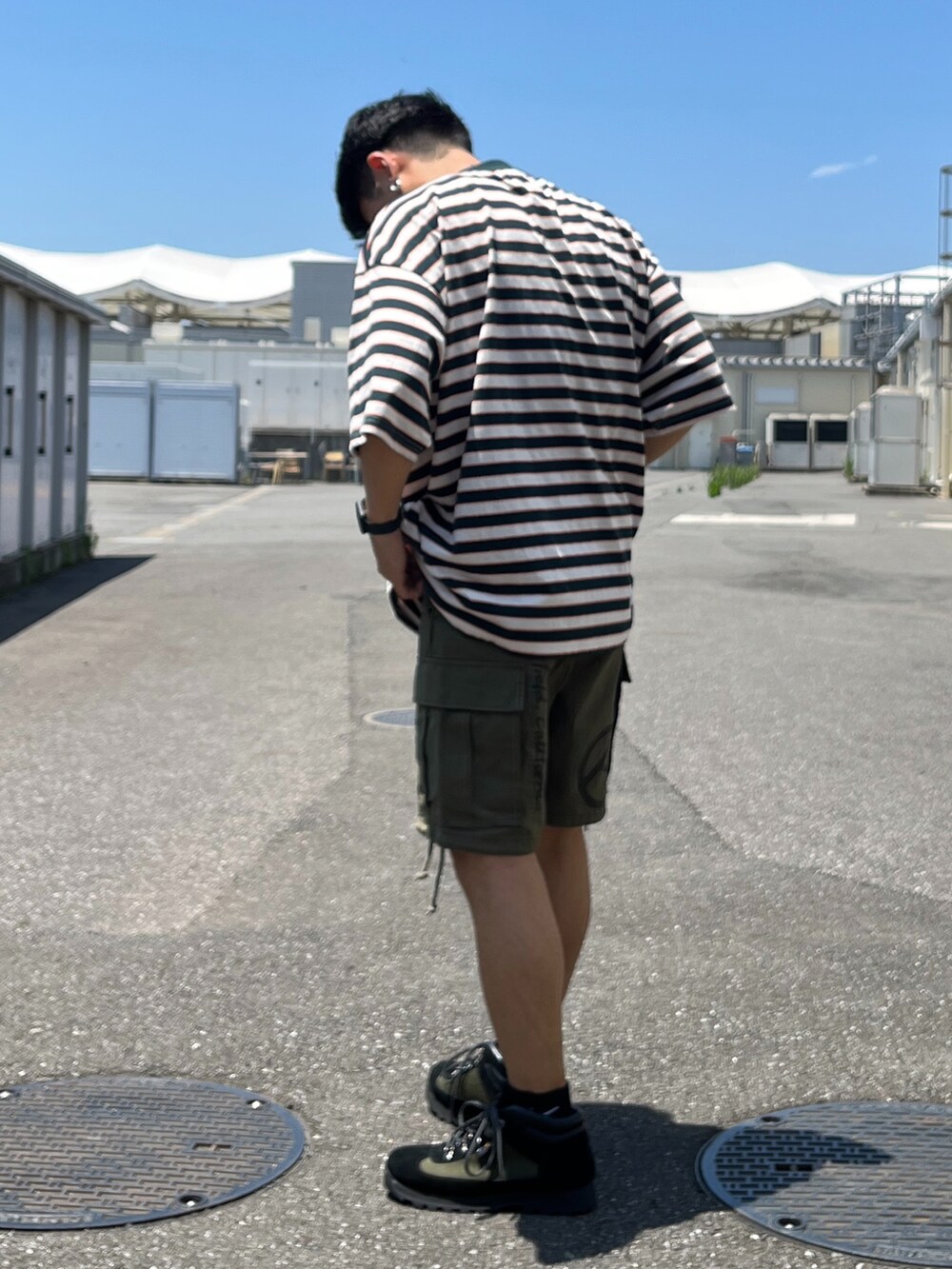 グリーン系のTシャツ/カットソー、グリーン系のカーゴパンツ、ブラック系のブーツを着用したメンズの夏コーディネートの3枚目の写真
