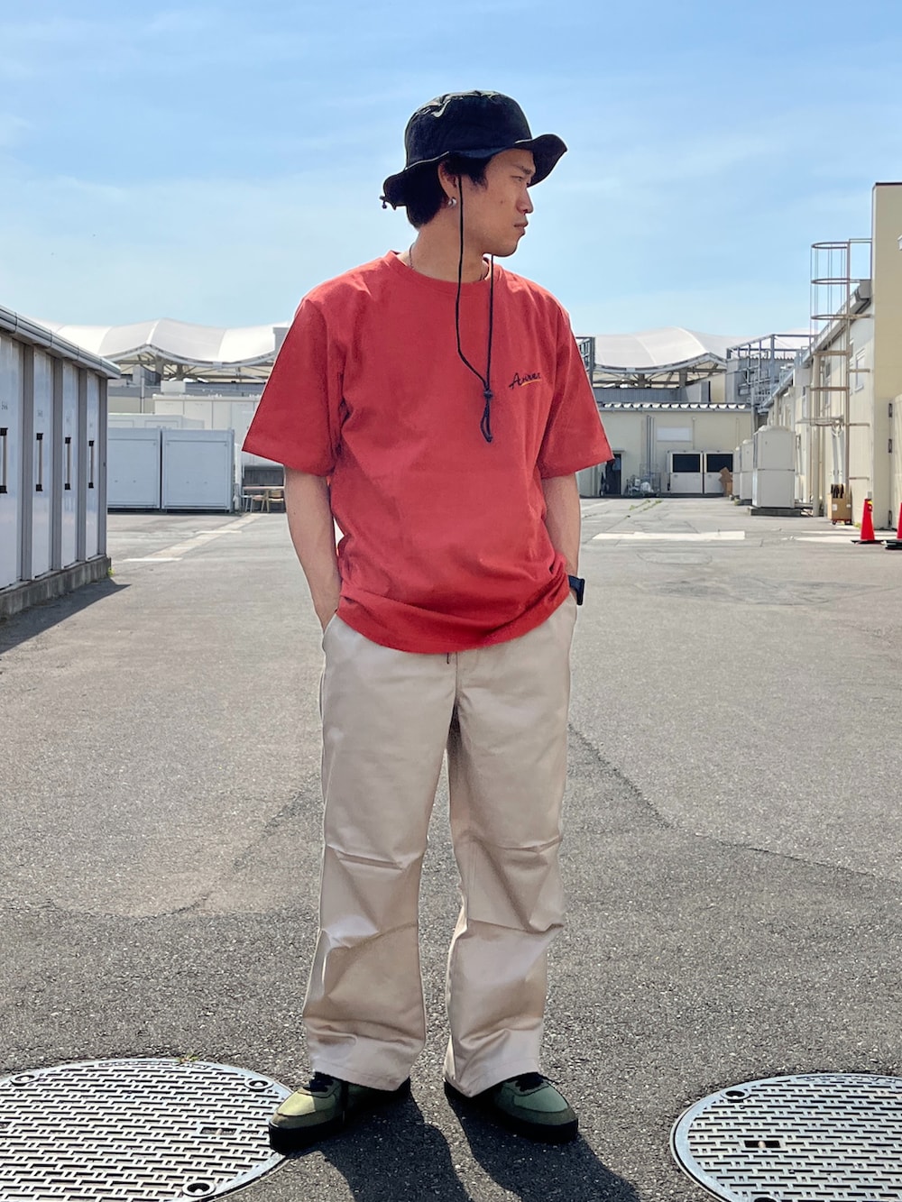 レッド系のTシャツ/カットソー、ベージュ系のパンツ、グリーン系のスニーカーを着用したメンズの春コーディネートの3枚目の写真
