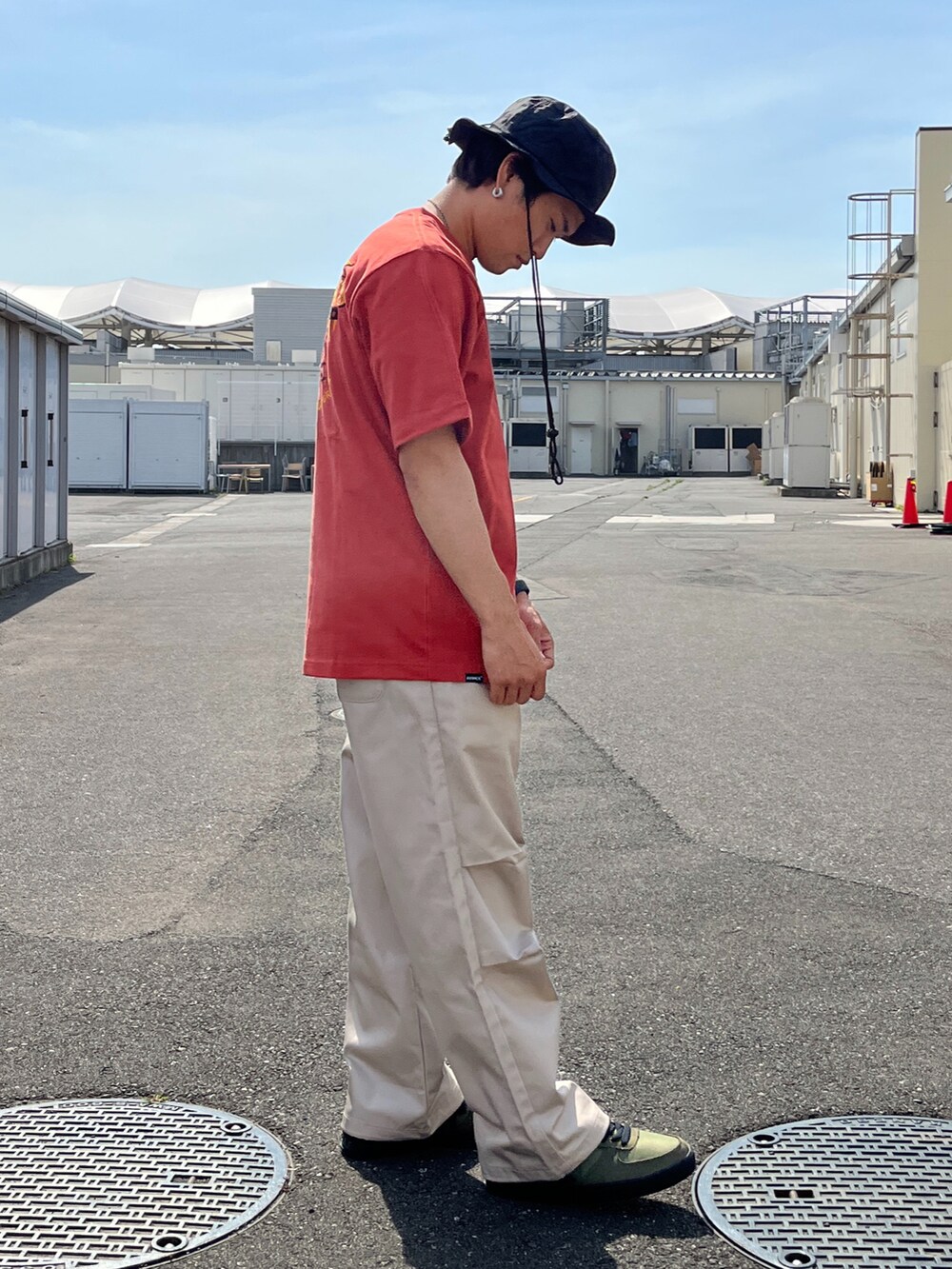 レッド系のTシャツ/カットソー、ベージュ系のパンツ、グリーン系のスニーカーを着用したメンズの春コーディネートの4枚目の写真