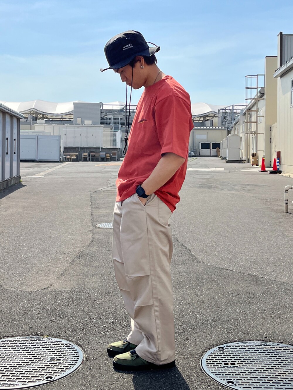 レッド系のTシャツ/カットソー、ベージュ系のパンツ、グリーン系のスニーカーを着用したメンズの春コーディネートの2枚目の写真