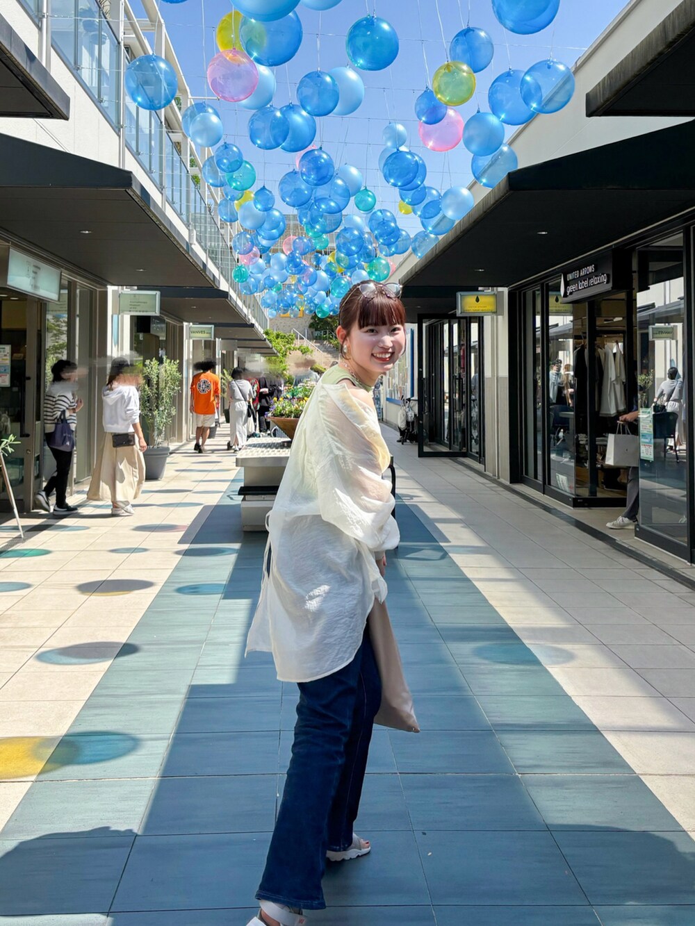 グリーン系のタンクトップ、ホワイト系のシャツ/ブラウス、ブルー系のデニムパンツを着用したレディースの夏コーディネートの3枚目の写真