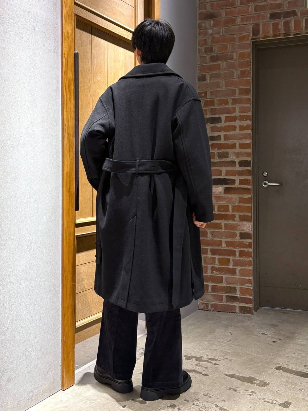 ブラック系のトレンチコート、ブラック系のスラックス、ブラック系のドレスシューズを着用したメンズの冬コーディネートの3枚目の写真