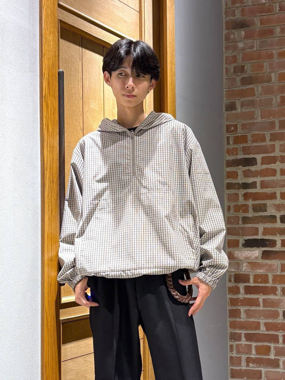 ブラック系のスニーカー、ブラック系のスラックス、ベージュ系のパーカーを着用したメンズの秋コーディネートの2枚目の写真