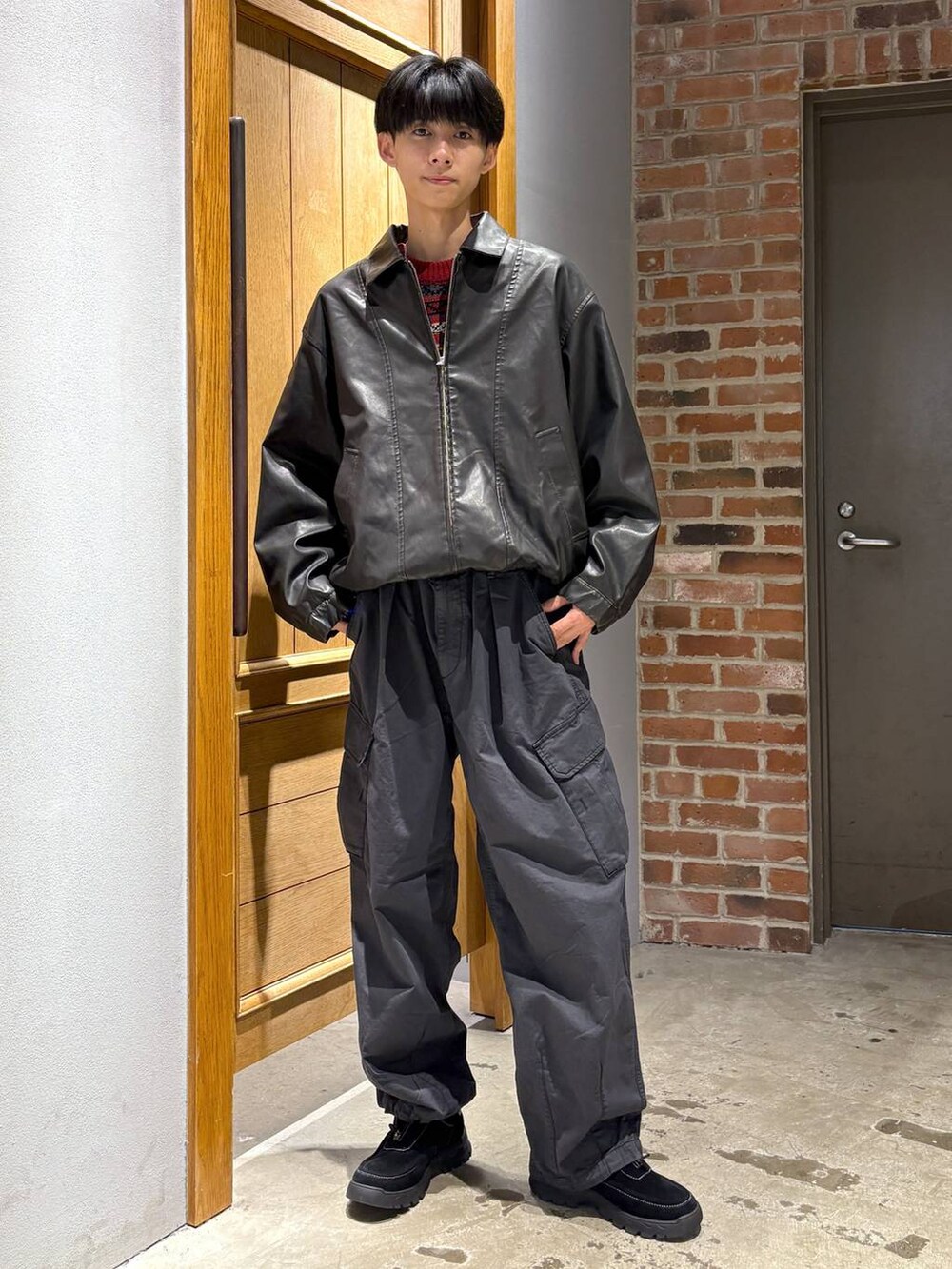 ブラック系のブルゾン、ブラック系のカーゴパンツ、ブラック系のスニーカーを着用したメンズの秋コーディネートの6枚目の写真
