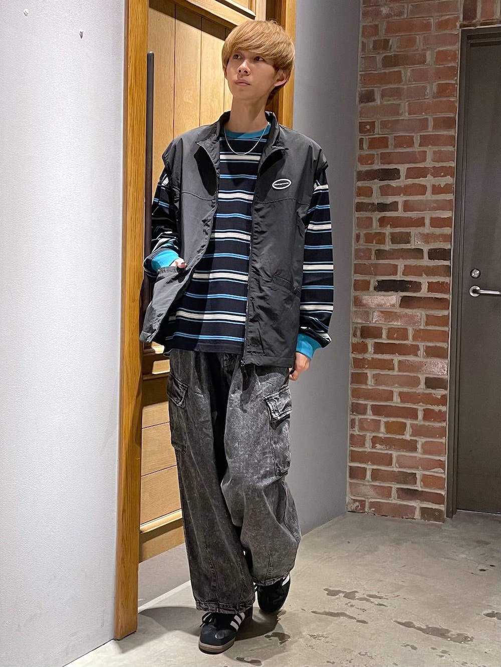 ブラック系のTシャツ/カットソー、グレー系のカーゴパンツ、ブラック系のベストを着用したメンズの春コーディネートの3枚目の写真