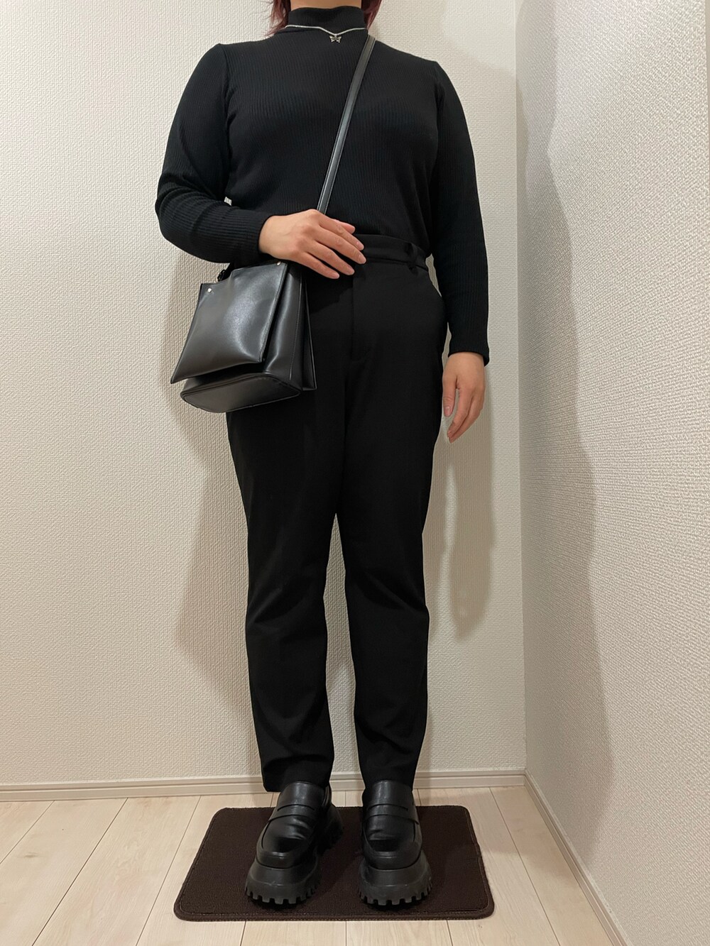 ブラック系のスラックス、ブラック系のローファー、ブラック系のチェスターコートを着用したレディースの春コーディネートの2枚目の写真