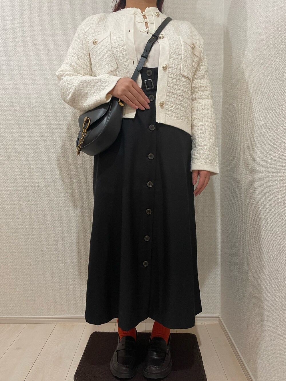 ブラック系のスカート、ブラック系のショルダーバッグ、ホワイト系のTシャツ/カットソーを着用したレディースの秋コーディネートの2枚目の写真