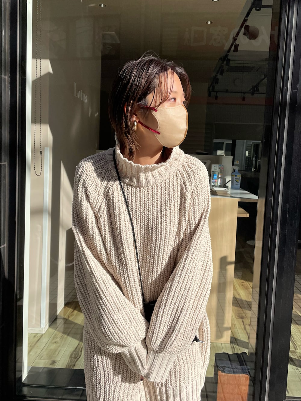 ベージュ系のワンピース、ホワイト系のパンツ、ブラック系のショルダーバッグを着用したレディースの冬コーディネートの2枚目の写真