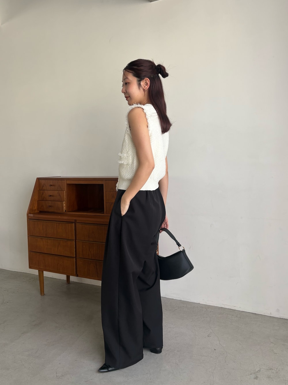 ブラック系のその他パンツ、ホワイト系のニット/セーター、ブラック系のショルダーバッグを着用したレディースの春コーディネートの2枚目の写真