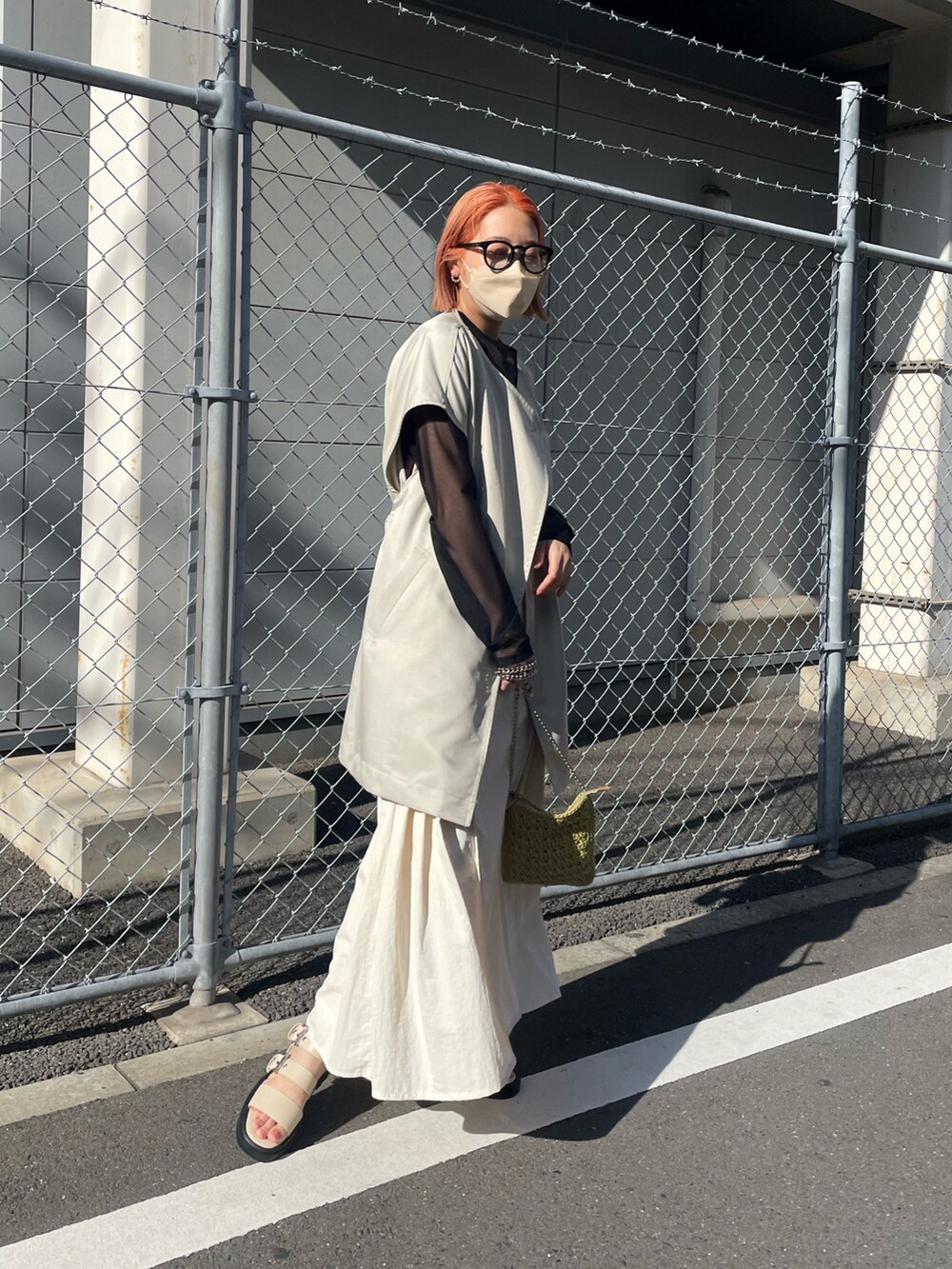 ホワイト系のサンダル、ホワイト系のスカート、ベージュ系のベストを着用したレディースの春コーディネートの2枚目の写真