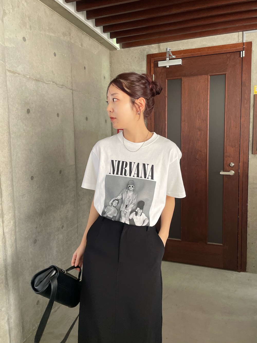 ブラック系のスカート、ホワイト系のTシャツ/カットソーを着用したレディースの春コーディネートの2枚目の写真